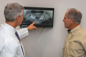 Oral Surgeon Teaching A Dental Patient About Dental Implants At Fusion Implant Center